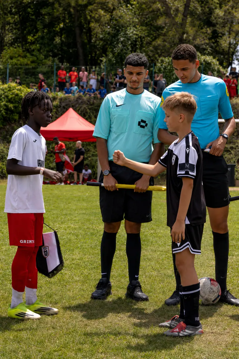 Le capitaine de l'Académie Révolution, fanion à la main, salue le capitaine adverse devant les arbitres avant le coup d'envoi d'un match de la Grinta Cup.