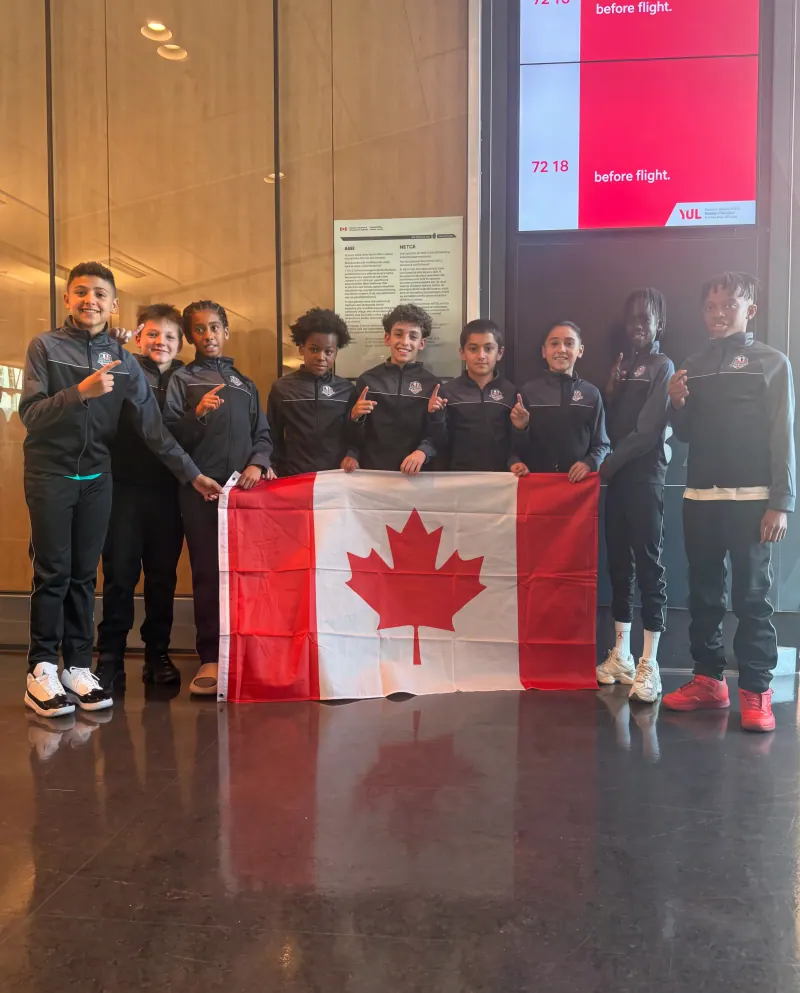 L'équipe de l'Académie de soccer Révolution de Montréal avec le drapeau du Canada à l'aéroport Montréal-Trudeau (YUL) avant son départ pour un tournoi